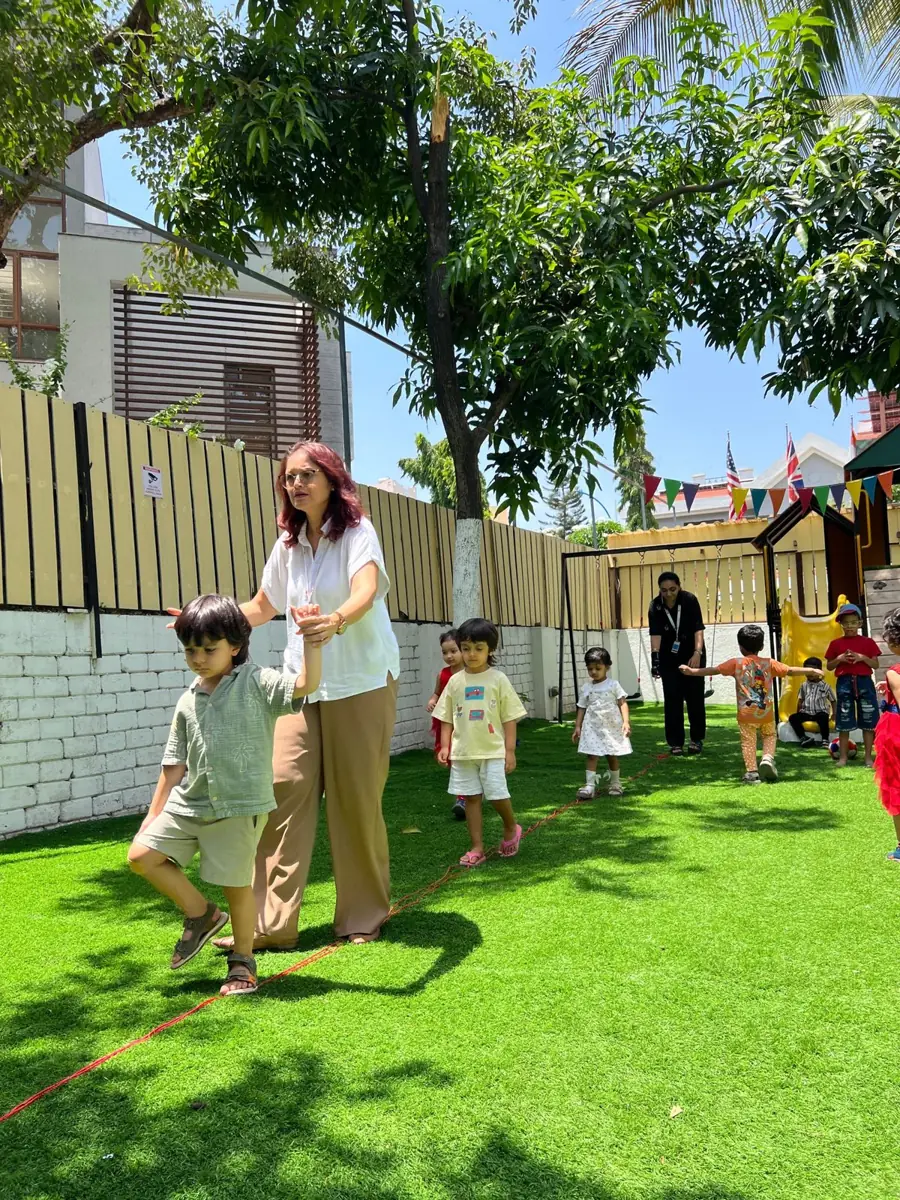 Children on a balance walk on the lawn with their teacher