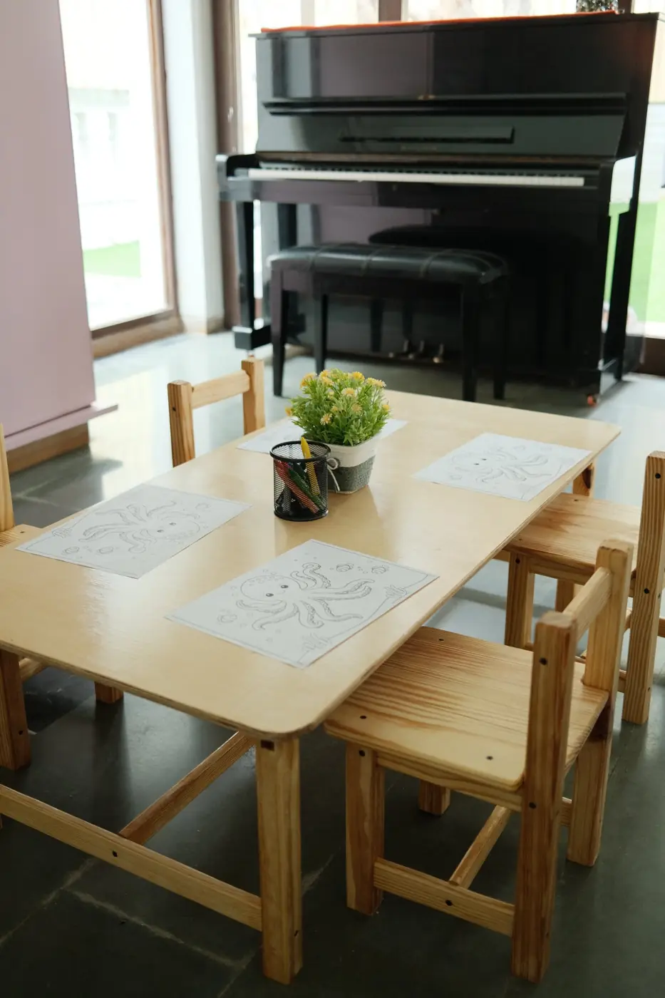 A preschool table set for colouring, with the piano behind